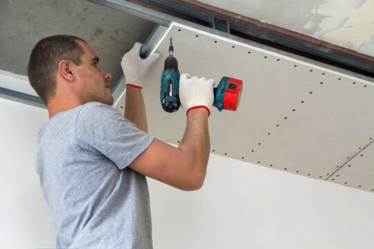 Construction worker assemble a suspended ceiling with drywall an